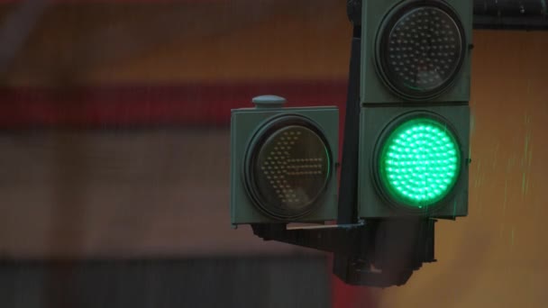 交通信号を閉じる 雨の降り道で道路の上にぶら下がる 点滅する黄色い矢と緑色の光で — ストック動画