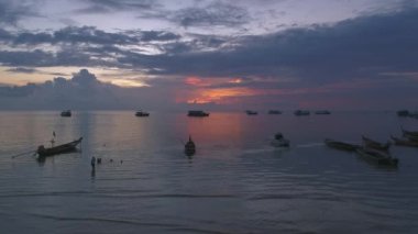 Okyanusta teknelerle Koh Tao üzerinde muhteşem bir gün batımı. Akşam ışığı, bulutlar gökyüzünü doldururken renkli bir deniz manzarası yaratır..