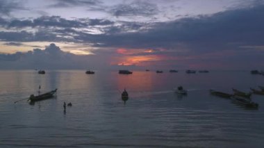 Yelkenli tekneler, güzel sahil şeridi ve güzel akşam ışıklarıyla baş döndürücü Tayland plajı günbatımı. Bu videoda Koh Tao 'nun sakin deniz manzarası sergilenmektedir..