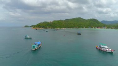 İnsansız hava aracı, Koh Tao, Tayland 'daki özgürlük plajındaki gemileri, kıyı şeridini ve mercan lagününün çarpıcı görüntülerini yakalıyor. Güzel manzarayı, kayalık kıyıları ve kristal berraklığında deniz manzarasını keşfedin. Canlı bir tanık.