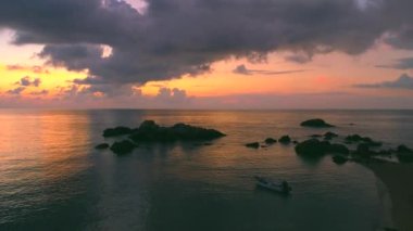 Koh Tao Sai Nuan Sahili 'nde Tayland gün batımını büyülüyor. Altın saat, kıyı şeridinde sıcak bir parıltı salıyor, tekneler sakin okyanusta sallanıyor. Canlı bulutlar renkli gökyüzünü boyar.