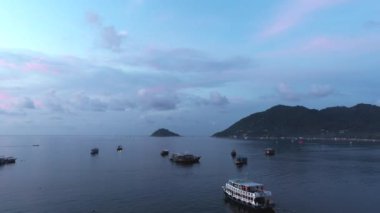 Koh Tao, Tayland 'daki teknelerde gün batımını seyret. Muhteşem Tayland adalarıyla çevrili Sairee Denizi 'nin renkli bulutlarının ve sakin deniz manzarasının tadını çıkarın..
