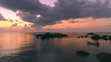 Koh Tao, Tayland 'da Sai Nuan Sahili' nde nefes kesici bir gün batımı. Sahil şeridi boyunca huzur içinde yüzen bir tekne gibi canlı renkler gökyüzünü dolduruyor. Tayland plajı güzelliğini tecrübe et..