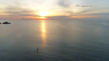 Renkli gökyüzü, okyanus ve iki sörfçü benekli Tayland plajı üzerinde manzaralı bir uçuş..