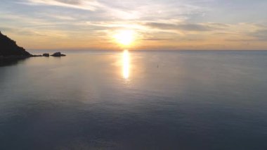 Koh Pha Ngan 'ın altın plajlarında çarpıcı gündoğumu uçuşunu yaşayın. Denizin güzelliğiyle çevrili, güneşe giden sakin sörfçüye hayret edin..
