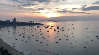 Pattaya şehrinde çarpıcı bir gün batımı, altın ışınlar gökyüzünde parlıyor, tekneler denizde yüzüyor, nefes kesici bir bakış açısı..