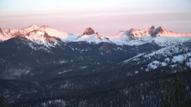 Sibirya Ergaki doğa parkındaki göz kamaştırıcı pembe dağlar. Karla kaplı bir manzara, nefes kesici bir günbatımı gökyüzü ve taiga orman zeminiyle. Rusya 'da kış macerası için mükemmel Sibirya vahşi doğası.