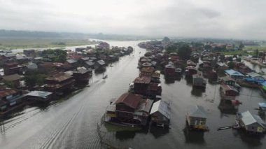 Myanmar 'daki Inle Gölü' nün sisli sularındaki teknelerin büyüleyici görüntüsü. Su üzerindeki köy ve ev huzurlu bir atmosfer yaratır..