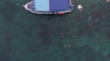 Tayland 'daki Koh Tao adası yakınlarındaki gemilerin hava görüntüsü. Teknelerin, bulutların, kıyı şeridinin ve günbatımının canlı renkleri büyüleyici bir deniz manzarası yaratır. Tayland sahillerinin dingin güzelliğini tecrübe et.