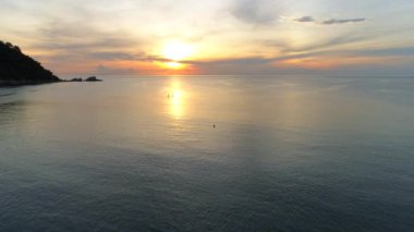 İki sörfçüyle Tayland sahilinde güzel bir gün doğumu, okyanusun üzerinde altın saat gökyüzü..