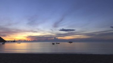 Tayland 'da tropikal bir adada gün doğumunda dans eden teknelerin çarpıcı sürati. Altın saat okyanusu aydınlatır, seyahat meraklıları için mükemmel bir varış yeri yaratır..