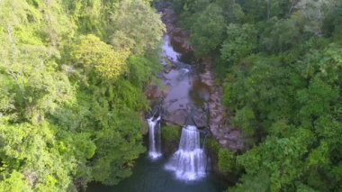 Video, yemyeşil ormandaki görkemli şelalenin nefes kesici görüntüsünü yakalıyor. Tayland 'da güneşin doğuşuyla birlikte doğanın dingin güzelliğini tecrübe et..