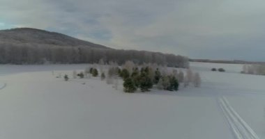Rusya, Hakassia 'da kış manzarası. Karla kaplı yol, pitoresk tarlalar ve ormanlar boyunca esiyor. Sersemletici günbatımı, sakin kış manzarasına sıcak bir ışık saçar. Seyahat meraklıları için mükemmel.