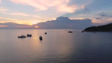 Tayland 'da gemi ve teknelerin üzerinden günbatımına uçuş. Okyanus manzarası ve güneş batarken Koh Tao adasının tadını çıkar. Tropik ada kaçamağı arayan seyahat meraklıları için mükemmel..