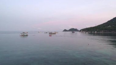 Berrak sularla çevrili bir mercan gölü, Koh Tao 'da tekneler ve pembe bulutlar..