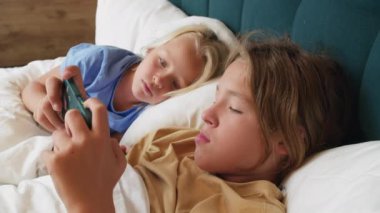 Bir çocuk akıllı telefon ekranına odaklanırken diğer bir çocuk izlesin