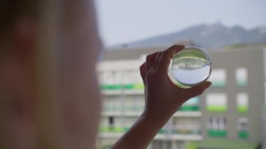 Ters dönmüş bir şehri yansıtan kristal bir küreyi tutan bir kıza yakın çekim