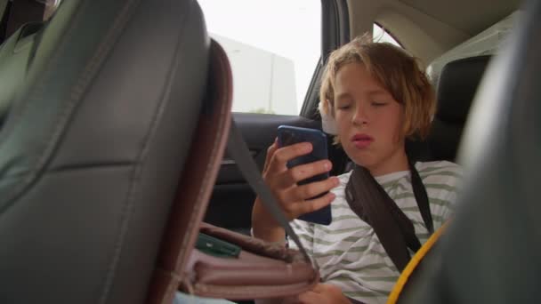 Letni Chłopiec Skupiony Swoim Smartfonie Tylnym Siedzeniu — Wideo stockowe