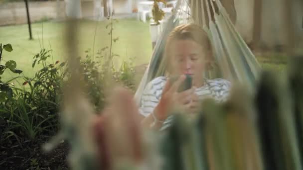 Rapaz Adolescente Deitado Rede Navegando Smartphone Jardim — Vídeo de Stock