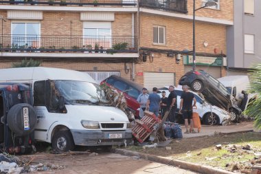VALENCIA, İSPA 31 Ekim 2024: Valencia, İspanya 'da meydana gelen ve devrilen araçlar ve enkazların caddeye saçıldığı sel felaketinin ardından meydana gelen hasarı değerlendiren vatandaşlar