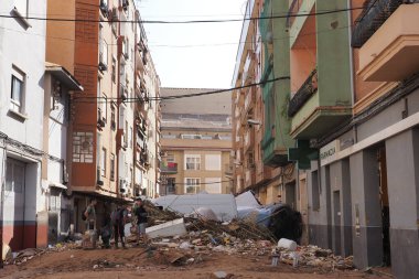 VALENCIA, İSPA 31 Ekim 2024: Valencia 'da bir şehir caddesinde meydana gelen sel felaketinin yıkıcı sonuçlarını enkaz ve hasarlı araçlarla izleyen vatandaşlar
