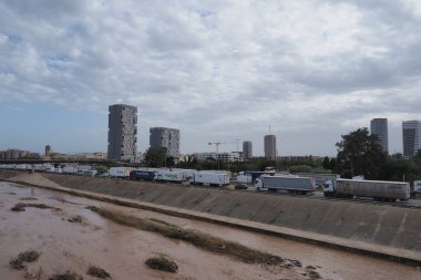 VALENCIA, İSPA 31 Ekim 2024: Valensiya, İspanya 'da sel basmış bir nehrin kenarına parkedilmiş kamyonlar, şiddetli hava koşullarının etkisini gösteriyor