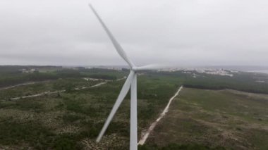 Bulutlu bir gökyüzü altında yenilenebilir enerji üreten rüzgar türbinleri sürdürülebilir güç çözümlerinin önemini vurgular