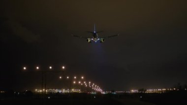 İniş ışıkları gece gökyüzünde parlayan pist işaretlerinin üzerinde olan uçaklar