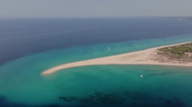 Yunanistan 'ın Halkidiki kentindeki Possidi Burnu' nun insansız hava aracı manzarası, turkuaz suları, görünür bir kum tabakası ve plajdaki insanlar.