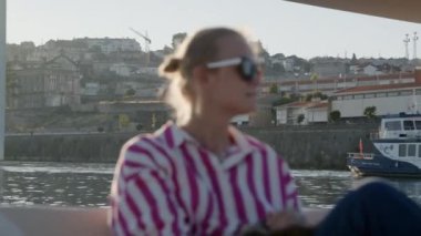 Güzel şehir manzarası ve rahat bir atmosferle çevrili bir tekne turunda güneşli bir günün tadını çıkaran bir turist.