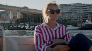 Portekiz, Porto 'daki Arrabida Köprüsü' nün altından geçen Douro Nehri 'ndeki dinlendirici tekne gezisinin tadını çıkaran genç bir kadın.