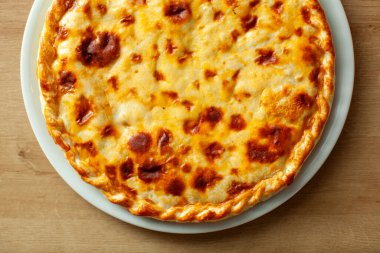 Golden-brown traditional Russian pie on a white plate set on a wooden table is a delicious example of Russian cuisine clipart