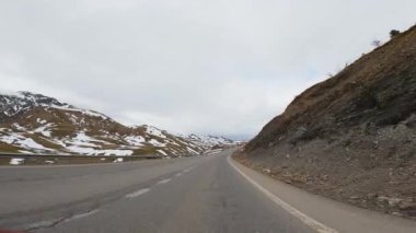 Karlı dağ yolu Alp arazisinde dönüyor, manzaralı vadiden geçiyor ve araçla kışın zorlu sürüş koşullarında yol alıyor.
