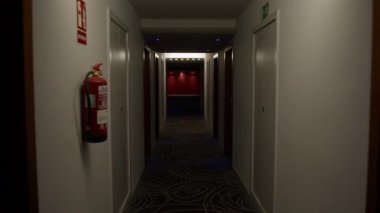 Loş ışık, ıssız otel koridorunda gizemli gölgeler bırakıyor. Karanlıktan yükselen canlı kırmızı asansörleri ve ürkütücü sinematik atmosferi yavaş yavaş gözler önüne seriyor.