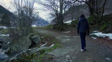 Karla kaplı dağ yolundan geçen yalnız yürüyüşçü huzurlu kış öğleden sonra manzaralı Pireneler Ulusal Parkı manzarasında vahşi doğa keşfi ve sakin doğa yaşam tarzını somutlaştırıyor.