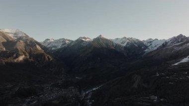 Hava görüntüsü - İspanya 'nın Pireneler kentindeki Benasque Vadisi' nde uzun gölgeler oluşturan ılık günbatımı ışığında parlayan karlı dağ zirveleri
