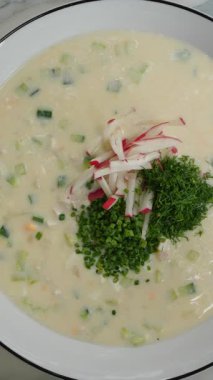 Dikey görüntüler Okroshka ve borscht, iki geleneksel çorba, dereotu, soğan, salatalık, turp ve yumurta gibi taze malzemelerle süslenerek lezzetlerini ve görsel cazibelerini artırıyor.