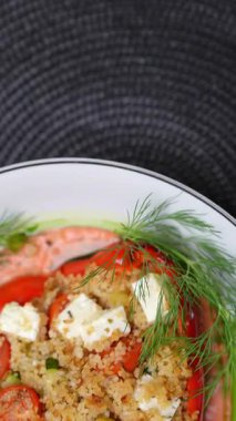 Dikey görüntüler vejetaryen dolgulu kırmızı dolma biber kuskus, feta, vişne domatesleri, kabak, beyaz tabakla süslenmiş pembe soslu dereotla dolu.