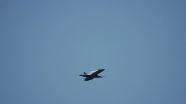 Modern savaş jeti, hava gösterisi sırasında mavi gökyüzünde bir bankacılık manevrası gerçekleştirir.