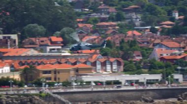 Uçan bıçaklı gri askeri helikopter uçuş sırasında denizin üstünde alçaktan uçar.