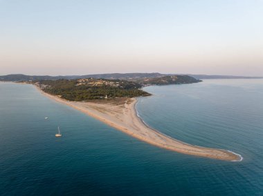 Possidi Burnu 'nun havadan görünüşü, Ege Denizi' ni ikiye bölen dar bir kum şeridi, yaz günbatımında kumlu bir sahil, yemyeşil bir bitki örtüsü ve sakin sulara sahip.