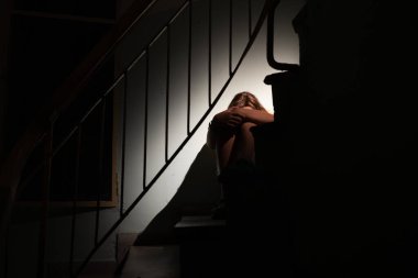 Yalnız ergen loş merdivenlere tünemiş, duygusal sıkıntı yaşıyor, incinebilirlik içsel psikolojik mücadeleyi ortaya çıkarıyor.