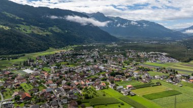 Avusturya 'nın Tyrol kentindeki Haiming' in havadan görünüşü, arka planda yerleşim alanları, tarım alanları ve görkemli Alpleri ile resmedilmiş manzarayı gösteriyor.