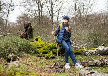 Sırt çantalı yosunlu kütüğün üzerinde dinleniyor, yemyeşil ormanlık arazide yürürken patika yiyeceği yiyor.
