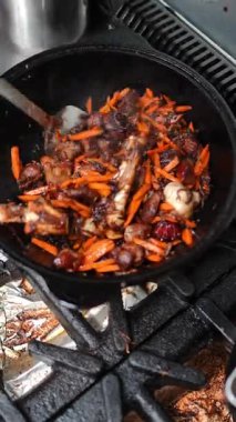 Yemek pişirme sürecinde lezzetli et ve canlı havuçlar tavada ustalıkla karıştırılırken, arka planda buhar yükseliyor ve gaz sobası ile mutfak teknikleri ve tatları vurgulanıyor.