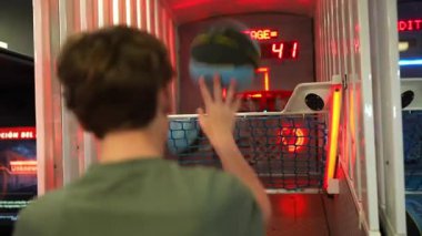 Genç erkek oyuncu, renkli ışıklar ve ilgi çekici bir oyun atmosferi ile çevrili bir şekilde ateş etmeye hazırlanırken, dinamik aksiyon sergiliyor.