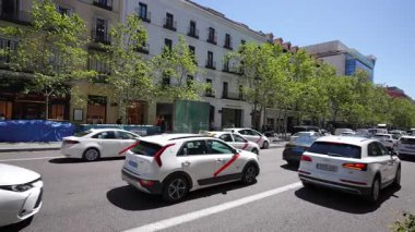 BARCELONA, SPAIN - 5 Temmuz 2025: Meşgul kentsel sokak sahnesi, verimli yeşillik ve mimari detaylarla çerçevelenmiş, şehir yaşamının enerjisini gösteren canlı şehir manzarasında hareket eden araçların dinamik akışını yakalar