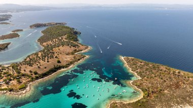 Yunanistan 'ın Sithonia kentindeki Vourvourou kıyı şeridinin hava manzarasında kristal berrak turkuaz sularda demirlemiş çok sayıda tekne yer alıyor.