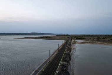 Fransa 'nın güneyindeki Occitanie kentindeki Etang de Leucate lagününden geçen bir demiryolu hattının havadan görünüşü.