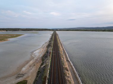 Leucate, Occitanie, Fransa 'da Etang de Leucate' den geçen demiryolu rayları, ulaşımın ve doğanın resimli bir görüntüsünü oluşturuyor.